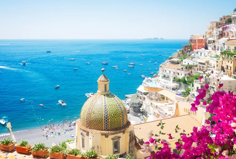 Positano beach and church dome with boats offshore